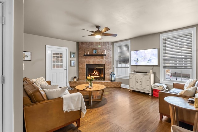 living area featuring a brick fireplace, wood finished floors, a wealth of natural light, and a ceiling fan