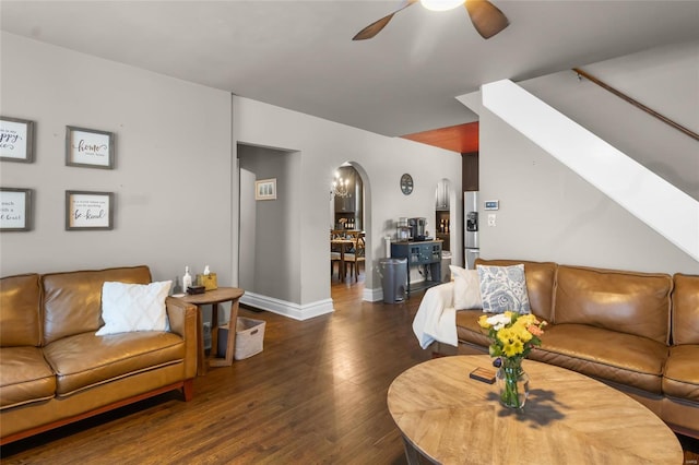 living area with baseboards, ceiling fan, arched walkways, and dark wood-type flooring