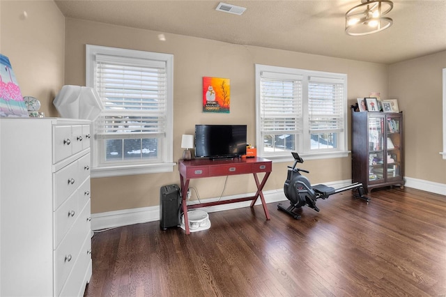 office area featuring dark wood-type flooring, visible vents, and baseboards