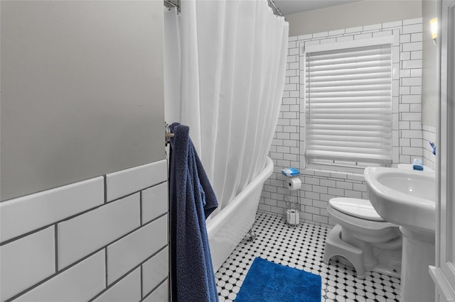 full bathroom featuring toilet, a wainscoted wall, tile walls, and shower / bathtub combination with curtain