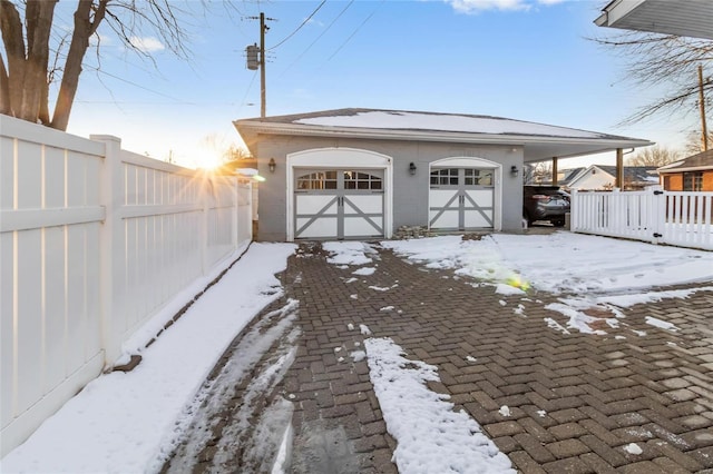 snow covered garage with fence