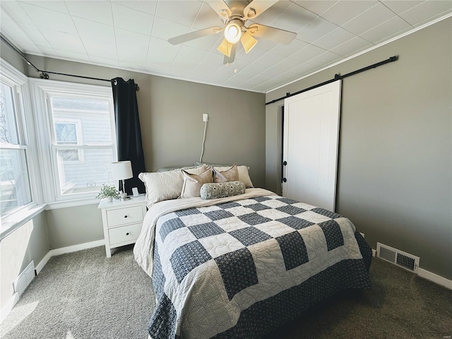 carpeted bedroom featuring visible vents, ceiling fan, baseboards, and a barn door