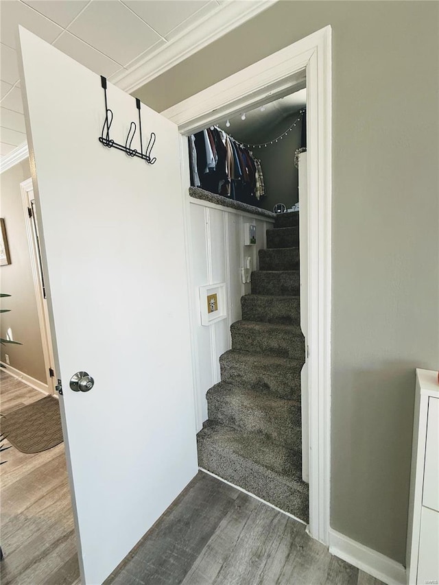 stairway with ornamental molding, baseboards, and wood finished floors