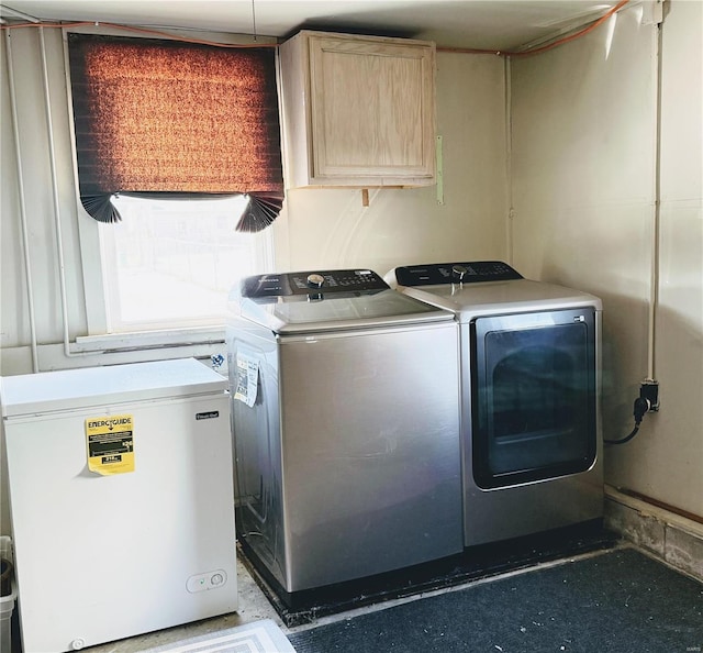 clothes washing area with washing machine and dryer and cabinet space