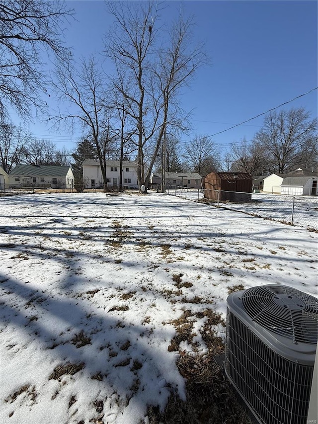 snowy yard with fence, a residential view, and central air condition unit