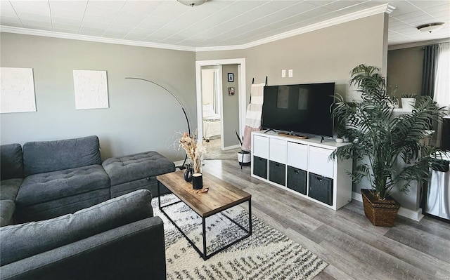 living area with baseboards, wood finished floors, and crown molding