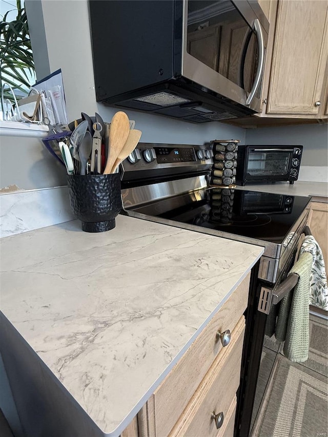 kitchen featuring a toaster, light brown cabinets, stainless steel appliances, and light countertops