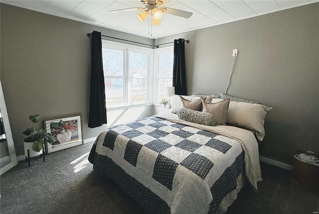 bedroom with ceiling fan, dark colored carpet, and baseboards