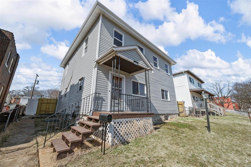 exterior space featuring covered porch, fence, and a lawn