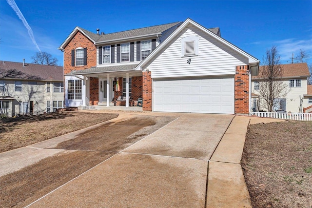 traditional-style home with a garage, concrete driveway, brick siding, and fence