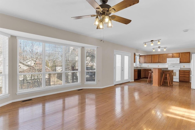 unfurnished living room featuring ceiling fan, light wood-type flooring, visible vents, and baseboards