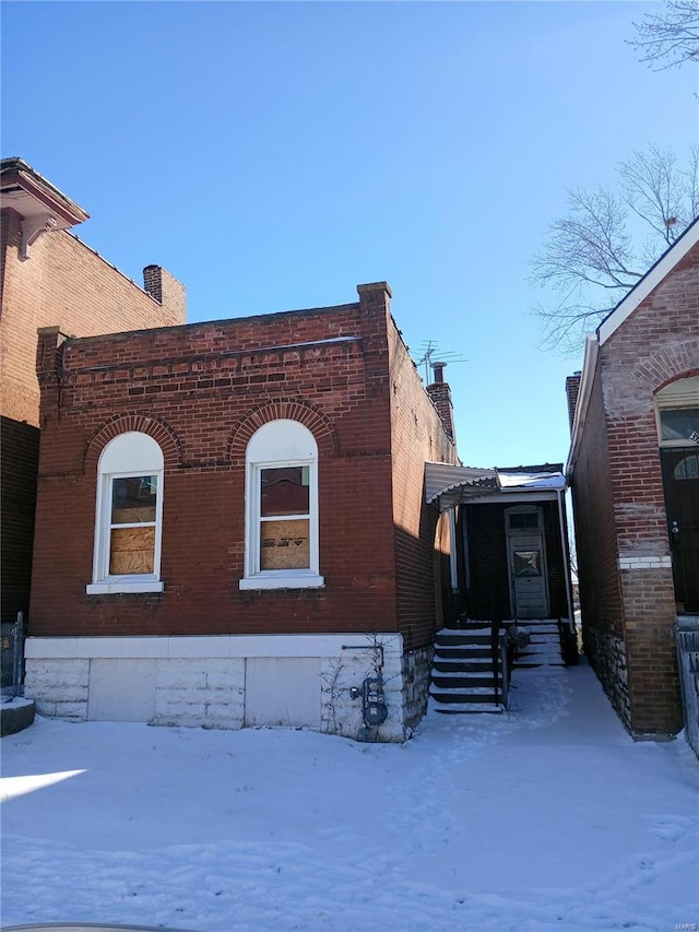 view of front of property with brick siding and a chimney