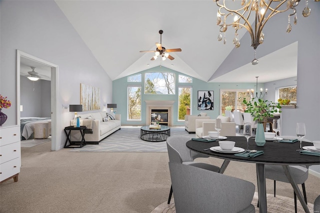 dining space with light carpet, high vaulted ceiling, and a glass covered fireplace