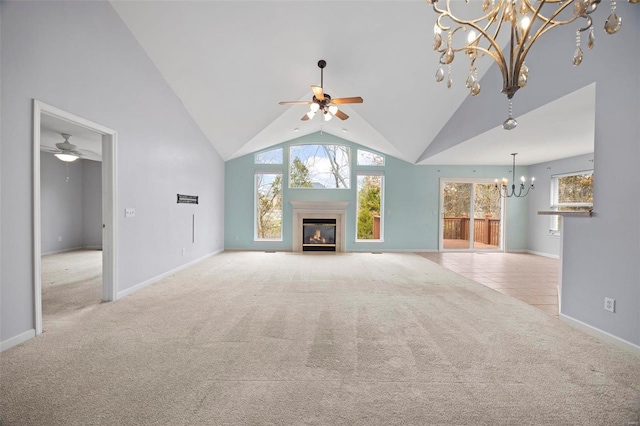 unfurnished living room featuring light carpet, high vaulted ceiling, ceiling fan with notable chandelier, and a glass covered fireplace