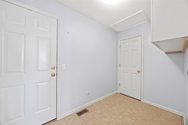 interior space featuring light tile patterned floors, attic access, visible vents, and baseboards