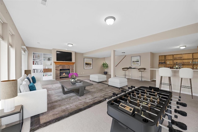 living room featuring a brick fireplace, visible vents, baseboards, and a dry bar