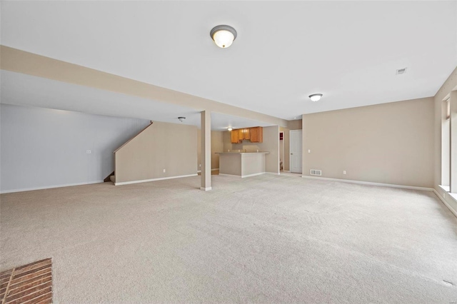 unfurnished living room with light carpet, visible vents, and baseboards