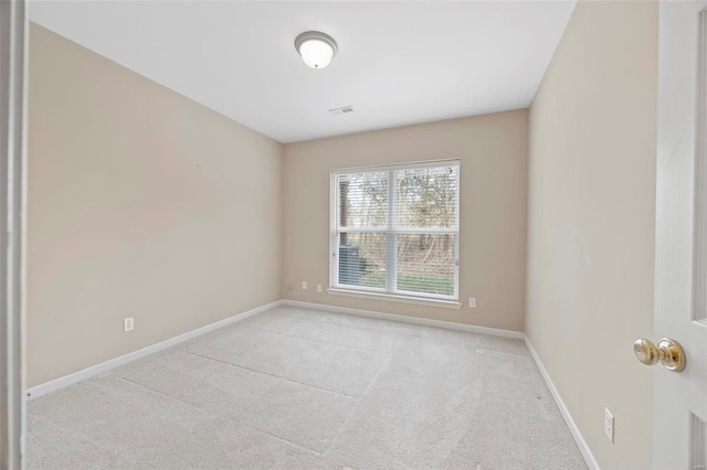 spare room featuring light carpet, visible vents, and baseboards