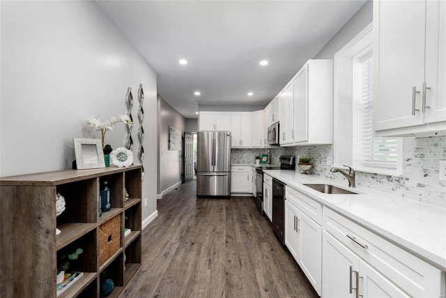 kitchen featuring light countertops, decorative backsplash, appliances with stainless steel finishes, white cabinetry, and a sink