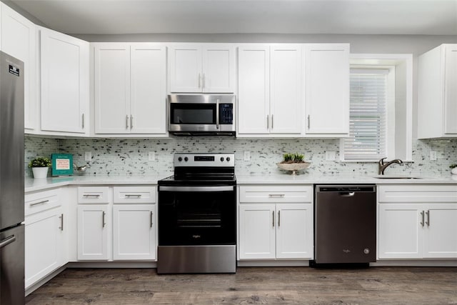 kitchen with stainless steel appliances, a sink, white cabinetry, light countertops, and dark wood-style floors