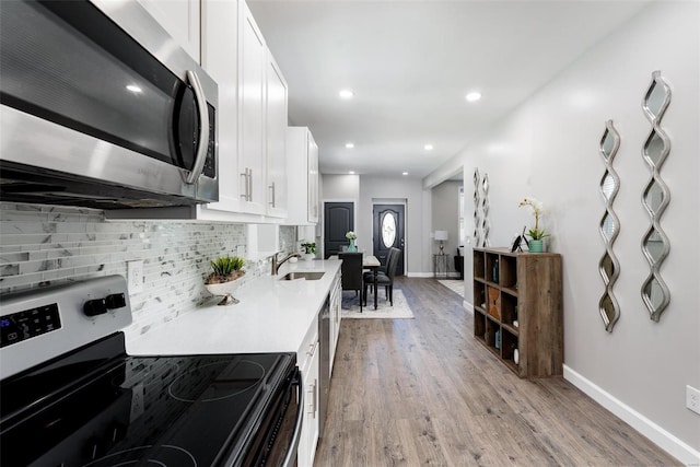 kitchen featuring white cabinetry, light wood-style floors, light countertops, appliances with stainless steel finishes, and tasteful backsplash