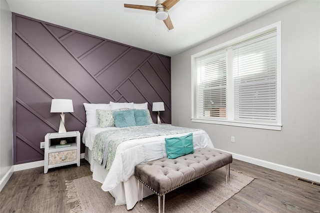 bedroom with dark wood-type flooring, visible vents, ceiling fan, and baseboards