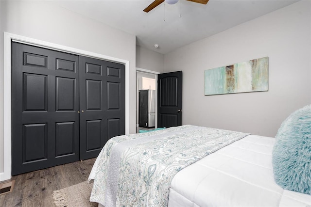 bedroom featuring a closet, visible vents, a ceiling fan, freestanding refrigerator, and wood finished floors