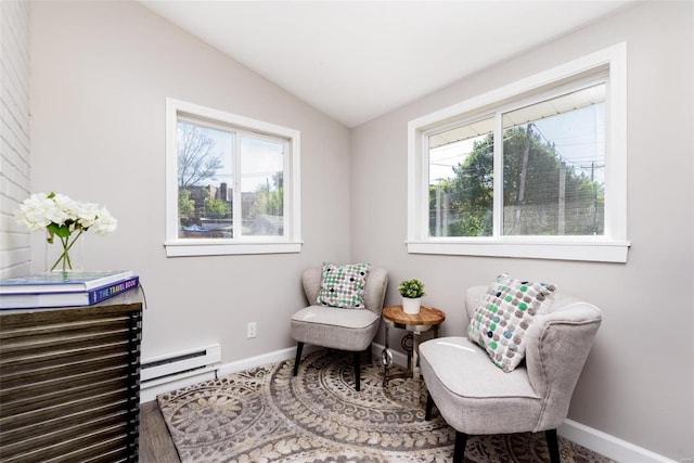 living area featuring vaulted ceiling, baseboard heating, plenty of natural light, and baseboards