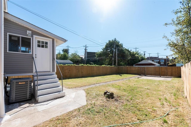 view of yard featuring entry steps, a fenced backyard, and central AC