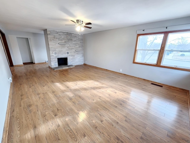 unfurnished living room featuring light wood-style flooring, a fireplace, visible vents, and a ceiling fan