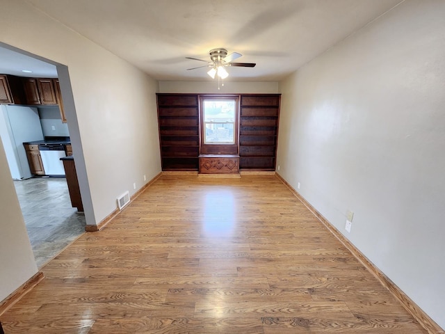 spare room with ceiling fan, light wood-style flooring, visible vents, and baseboards