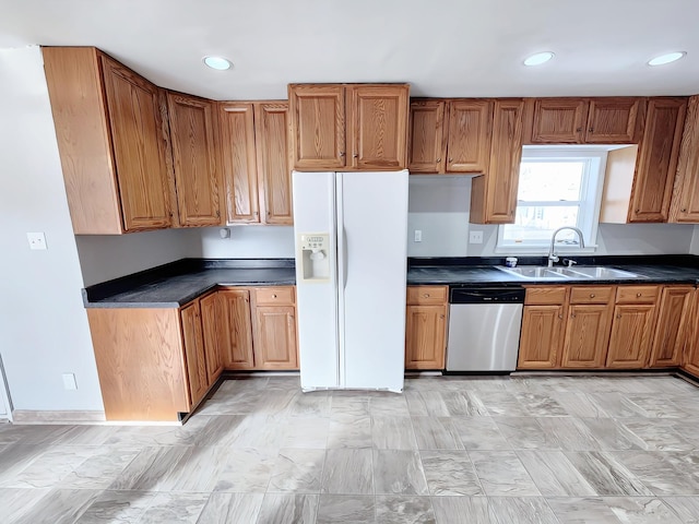 kitchen featuring a sink, brown cabinets, dishwasher, white fridge with ice dispenser, and dark countertops