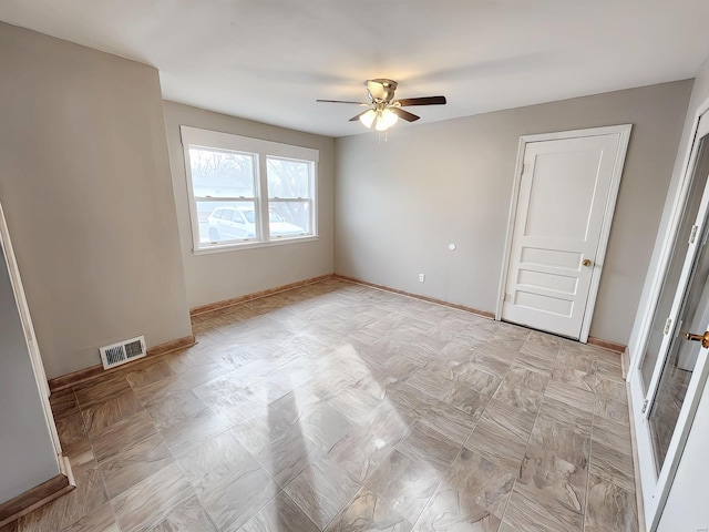 spare room featuring ceiling fan, visible vents, and baseboards