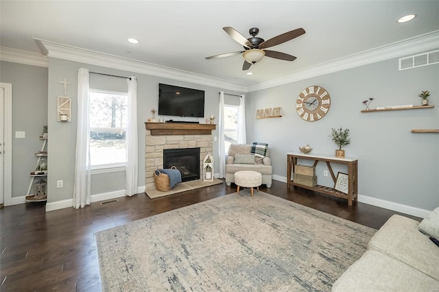 living room with a stone fireplace, crown molding, baseboards, and wood finished floors