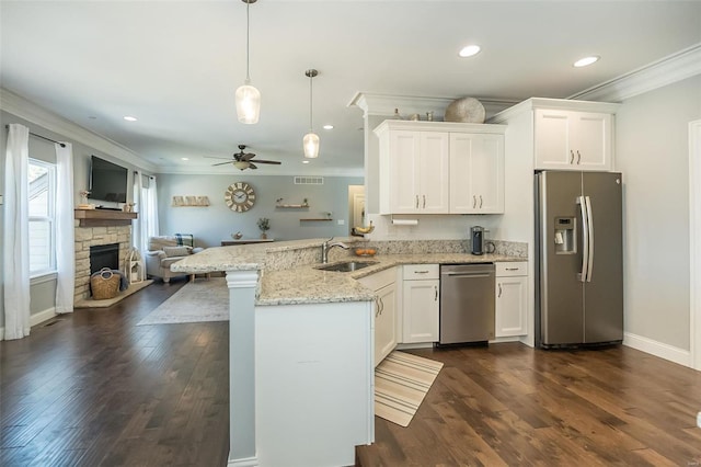 kitchen featuring a sink, open floor plan, a peninsula, appliances with stainless steel finishes, and crown molding