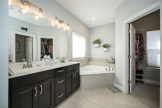 bathroom featuring a sink, a walk in closet, a bath, and double vanity