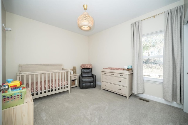 bedroom with a nursery area, carpet, visible vents, and baseboards