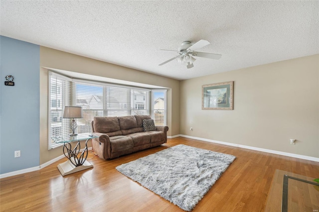 living area with a textured ceiling, light wood-type flooring, and baseboards