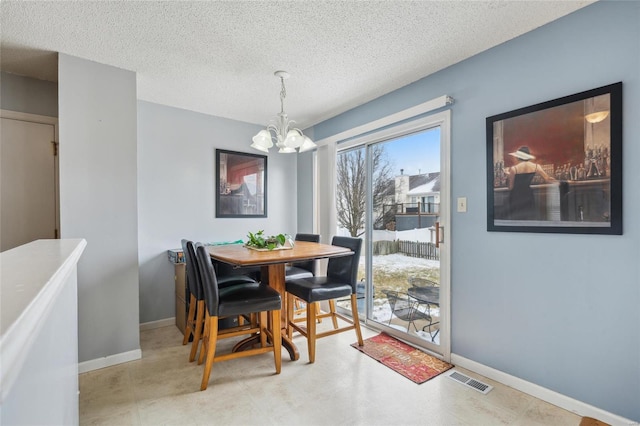 dining space with visible vents, a textured ceiling, baseboards, and a notable chandelier