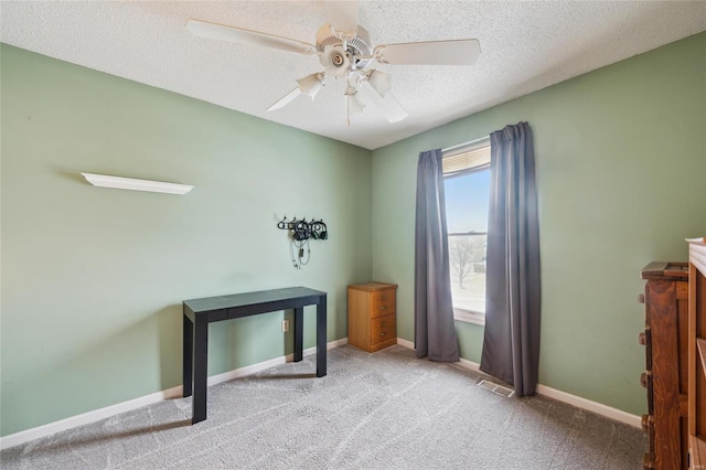 interior space featuring a textured ceiling, ceiling fan, light colored carpet, visible vents, and baseboards