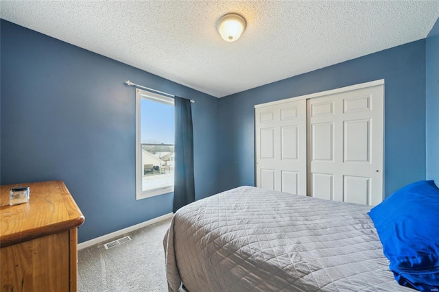 carpeted bedroom featuring a textured ceiling, a closet, visible vents, and baseboards