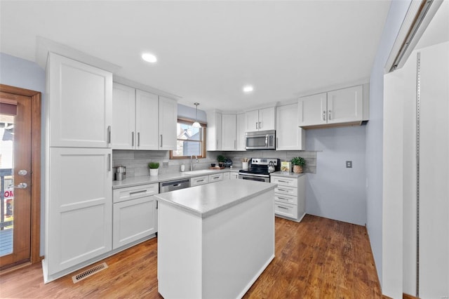 kitchen featuring visible vents, decorative backsplash, appliances with stainless steel finishes, white cabinets, and a sink