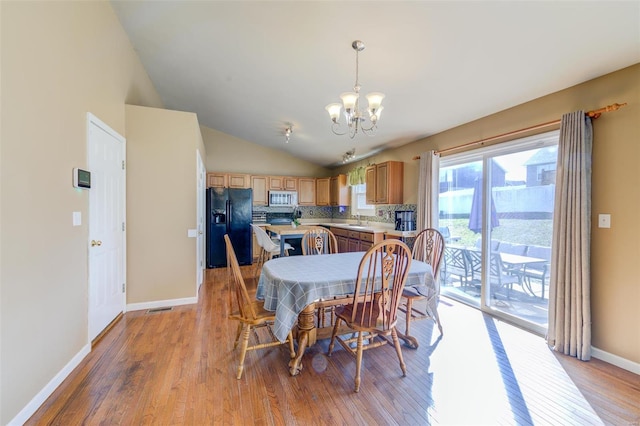 dining room with a notable chandelier, visible vents, light wood-style floors, vaulted ceiling, and baseboards