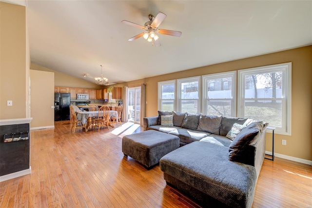 living room featuring lofted ceiling, ceiling fan with notable chandelier, light wood-style flooring, and baseboards