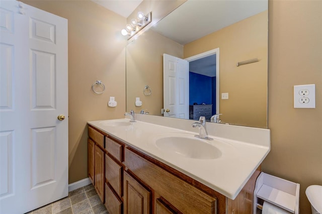 bathroom featuring baseboards, a sink, ensuite bath, and double vanity