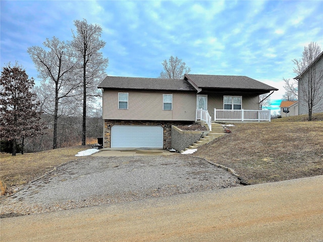 view of front of property with a garage, stone siding, a porch, and gravel driveway