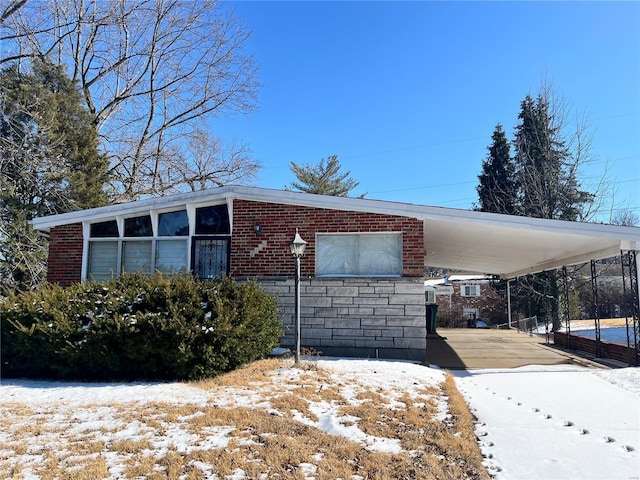 exterior space with a carport, brick siding, and concrete driveway