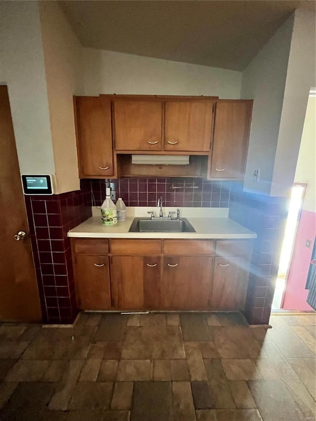 kitchen featuring brown cabinetry, light countertops, and a sink