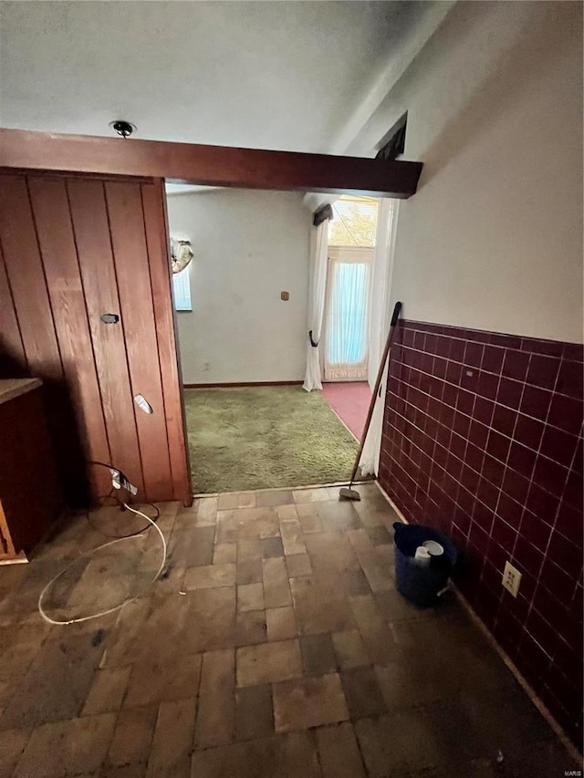 hallway with tile walls and light colored carpet