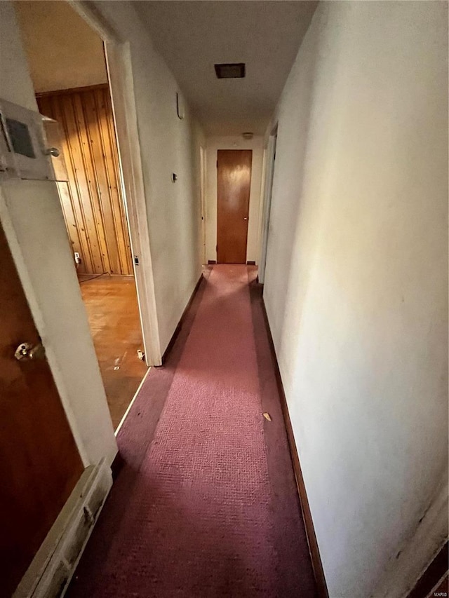 hallway with dark carpet and baseboards